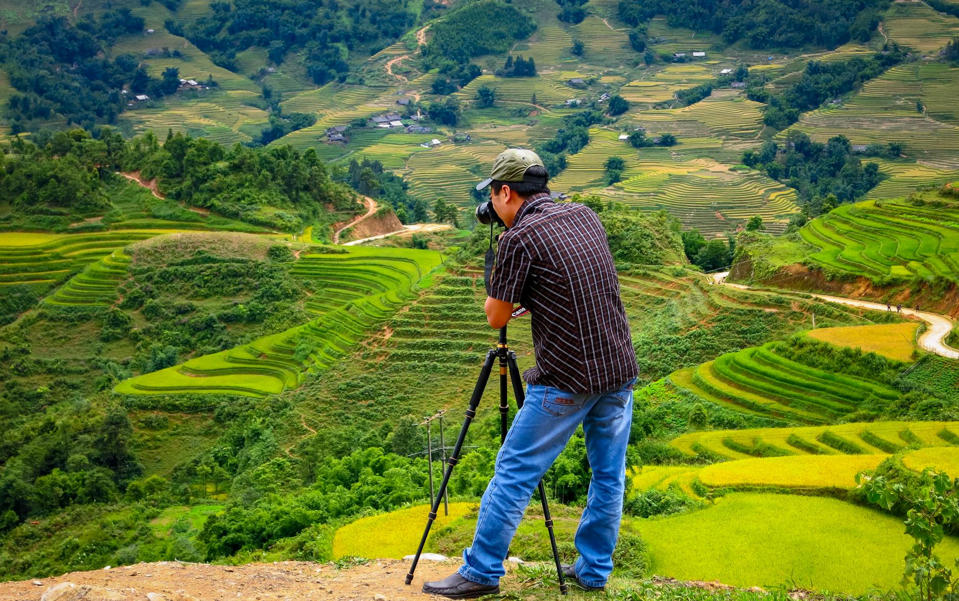 Fotograf z aparatem na statywie fotografuje tarasy ryżowe w Lào Cai