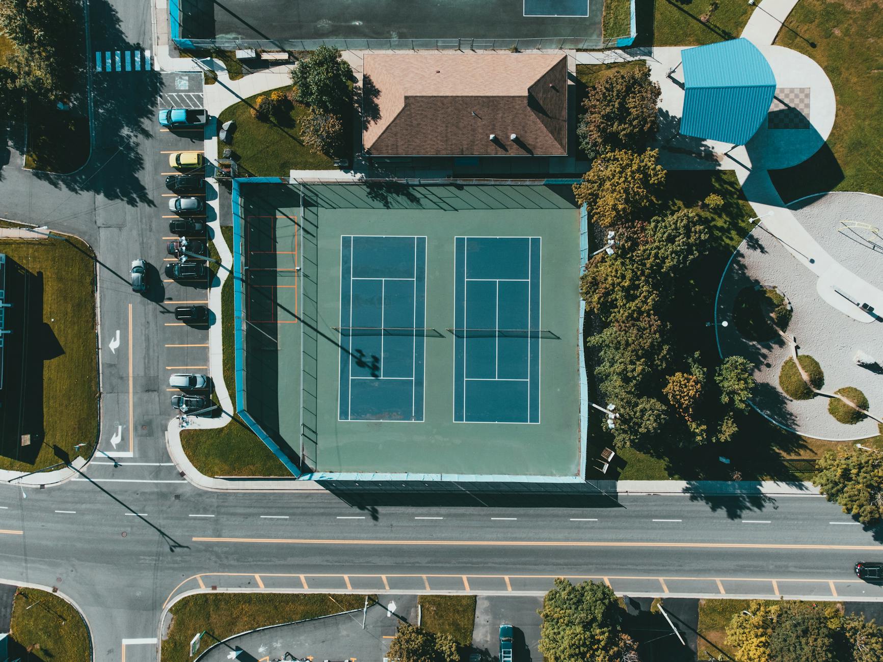 Korty tenisowe z lotu ptaka w otoczeniu bloków i zieleni
