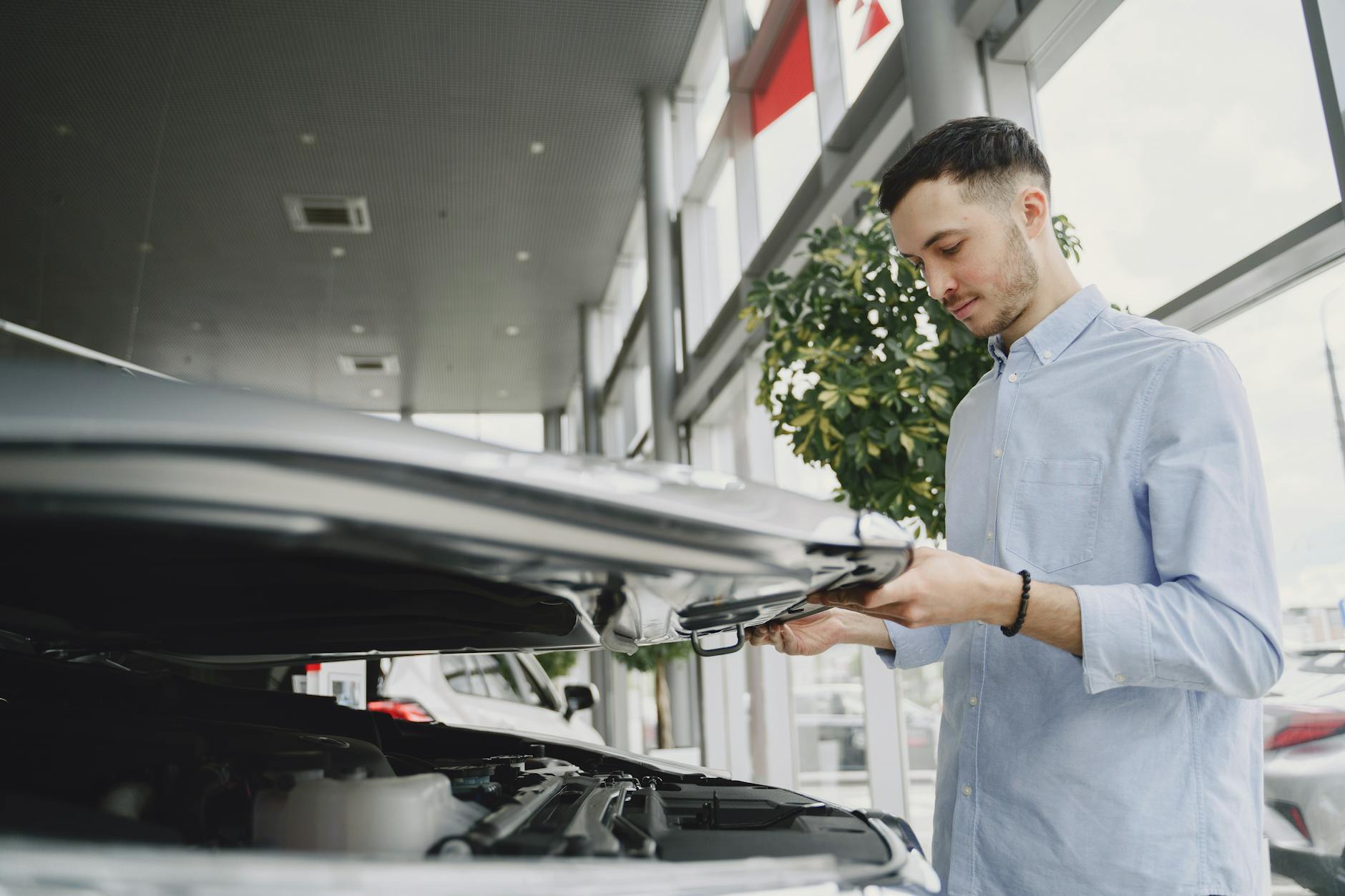 Jak bezpiecznie kupić auto używane w komisie: praktyczny poradnik krok po kroku Młody mężczyzna ogląda silnik używanego auta w salonie komisowym