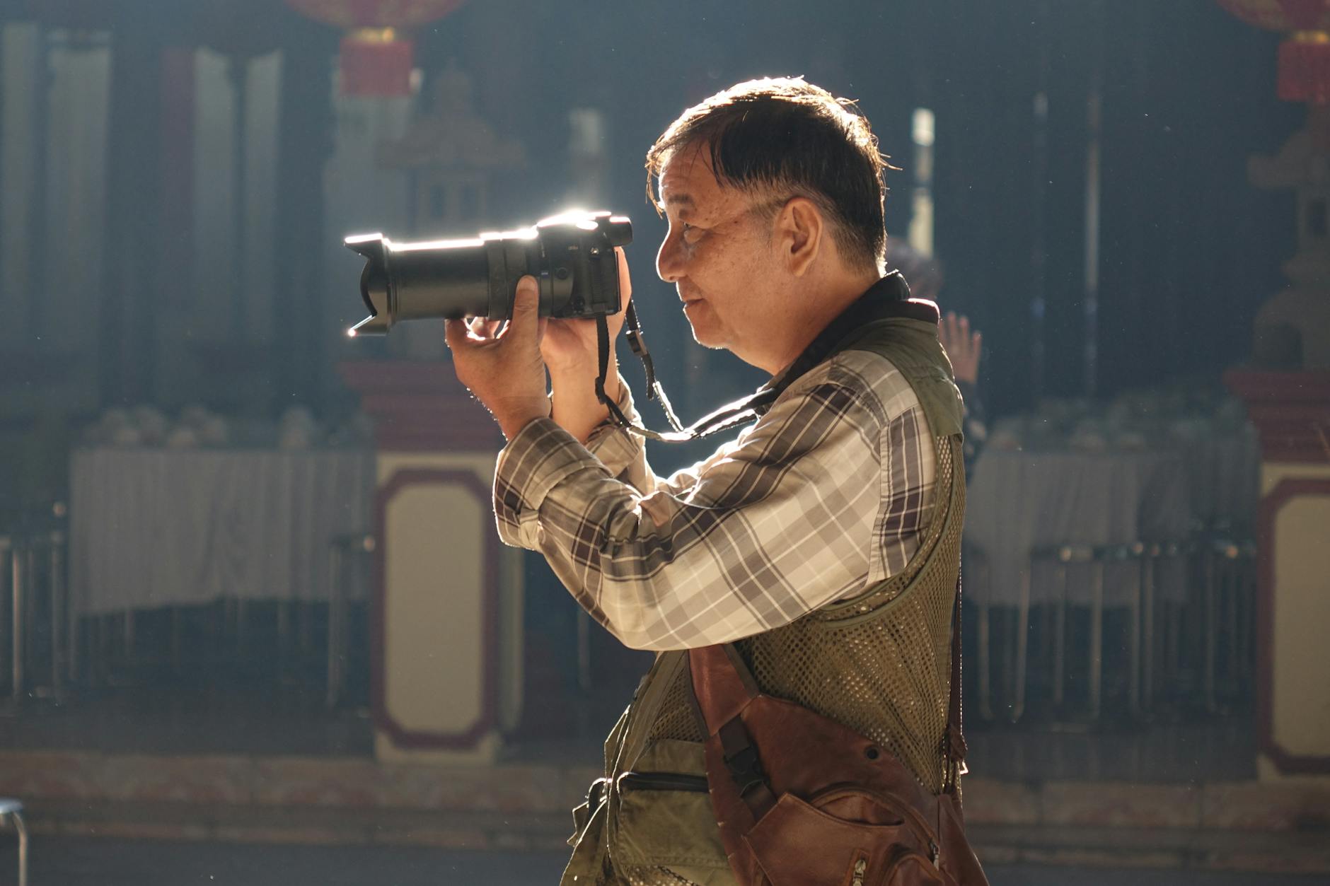 Starszy mężczyzna fotografuje w pomieszczeniu lustrzanką cyfrową