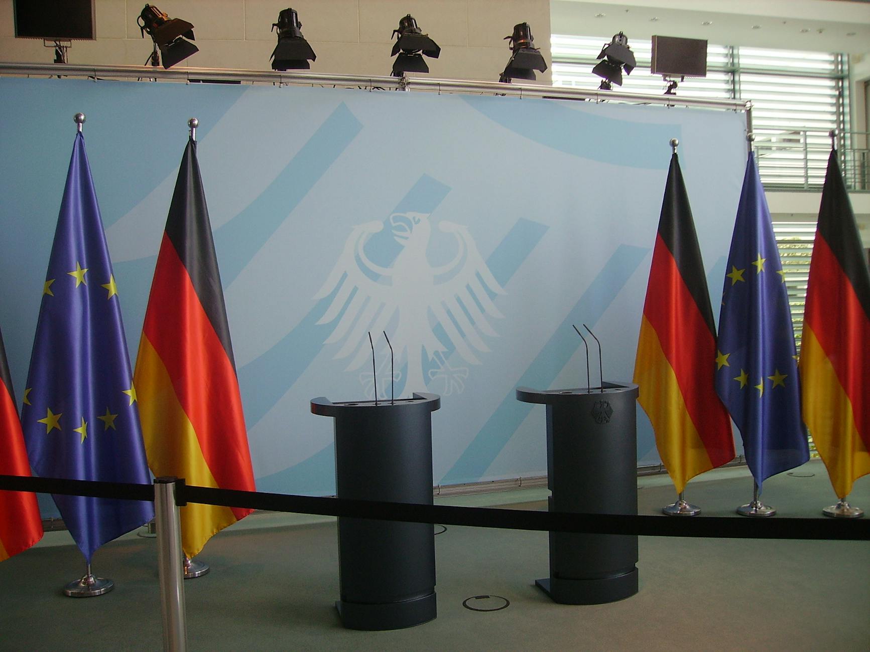 Puste mównice na tle flag Niemiec i Unii Europejskiej