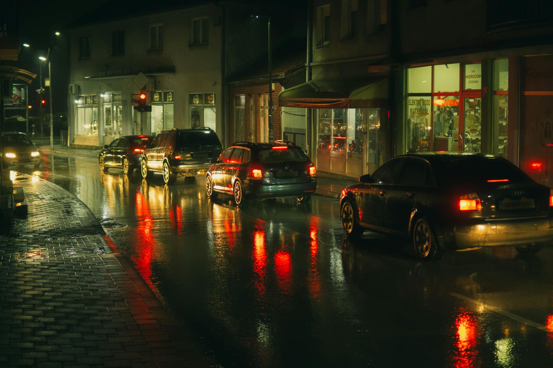 Jak poprawić technikę hamowania awaryjnego na mokrej nawierzchni Samochody w nocnym deszczu, czerwone światła hamowania odbite na jezdni